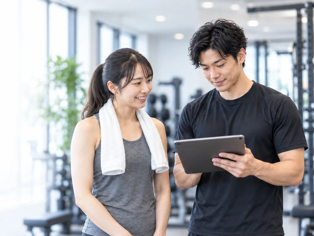 タブレットで記録を確認するトレーナーと会員